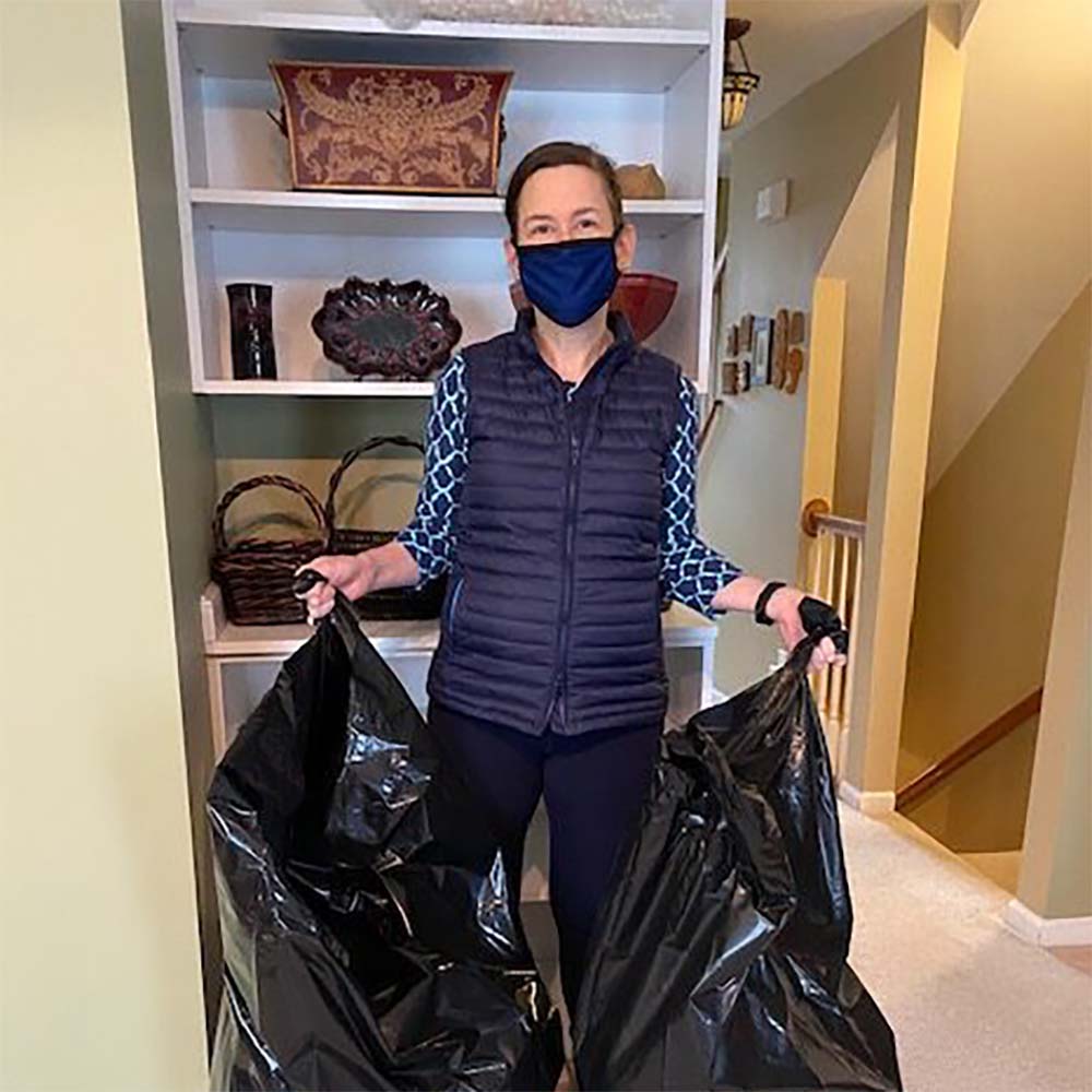 Photo of women wearing COVID-19 mask and holding two trash bags