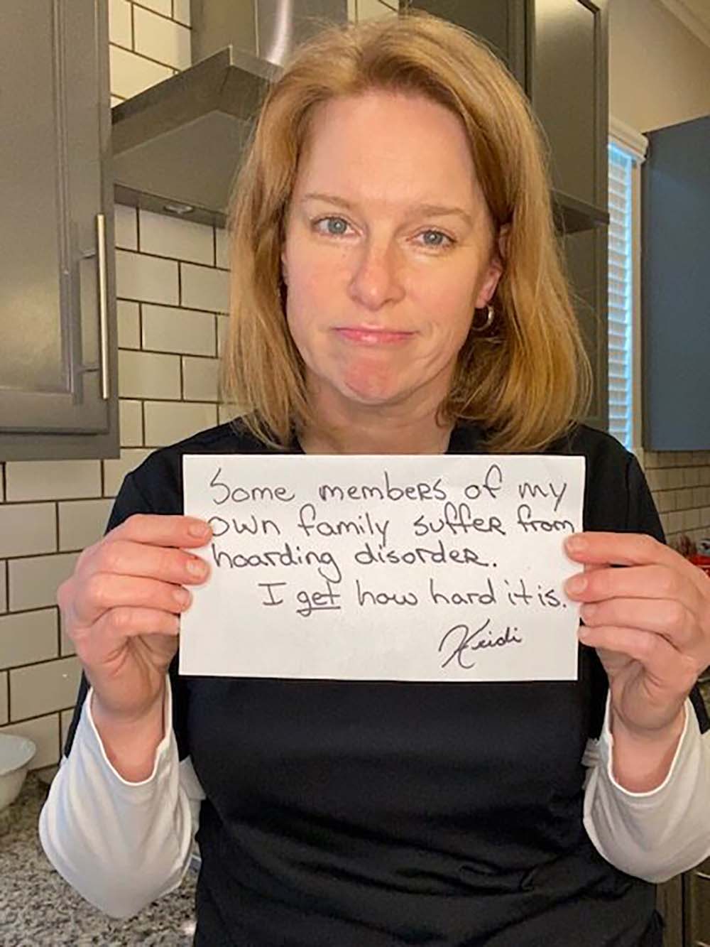 Heidi Roed holding a sign indicating members of her family have hoarding disorder